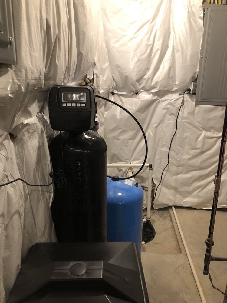 Softener next to a blue well pressure tank in a new-construction basement