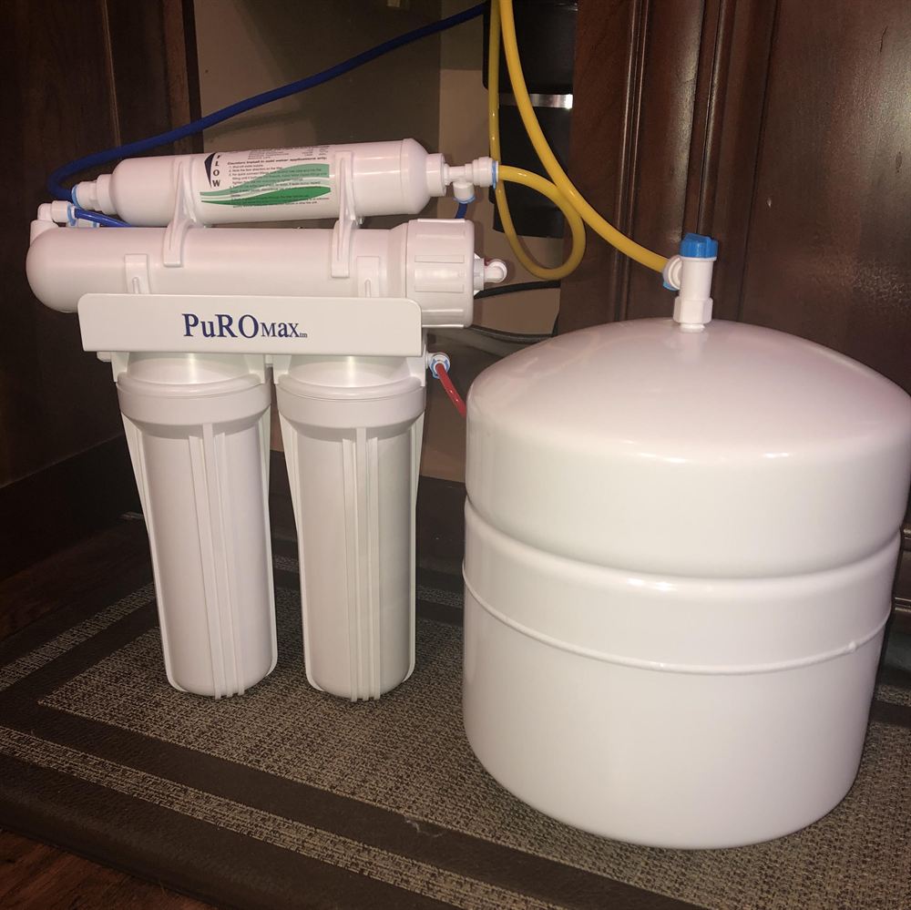 PuROMax four-stage reverse osmosis unit and white storage tank under a kitchen sink